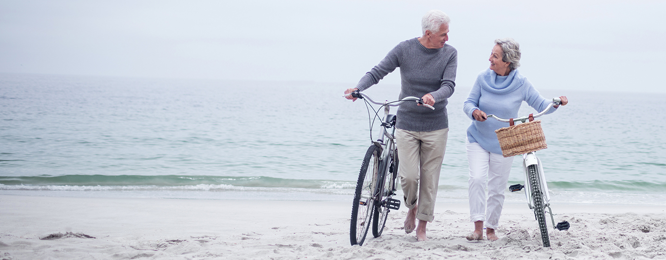 An elderly couple enjoying a bicycle ride on the beach